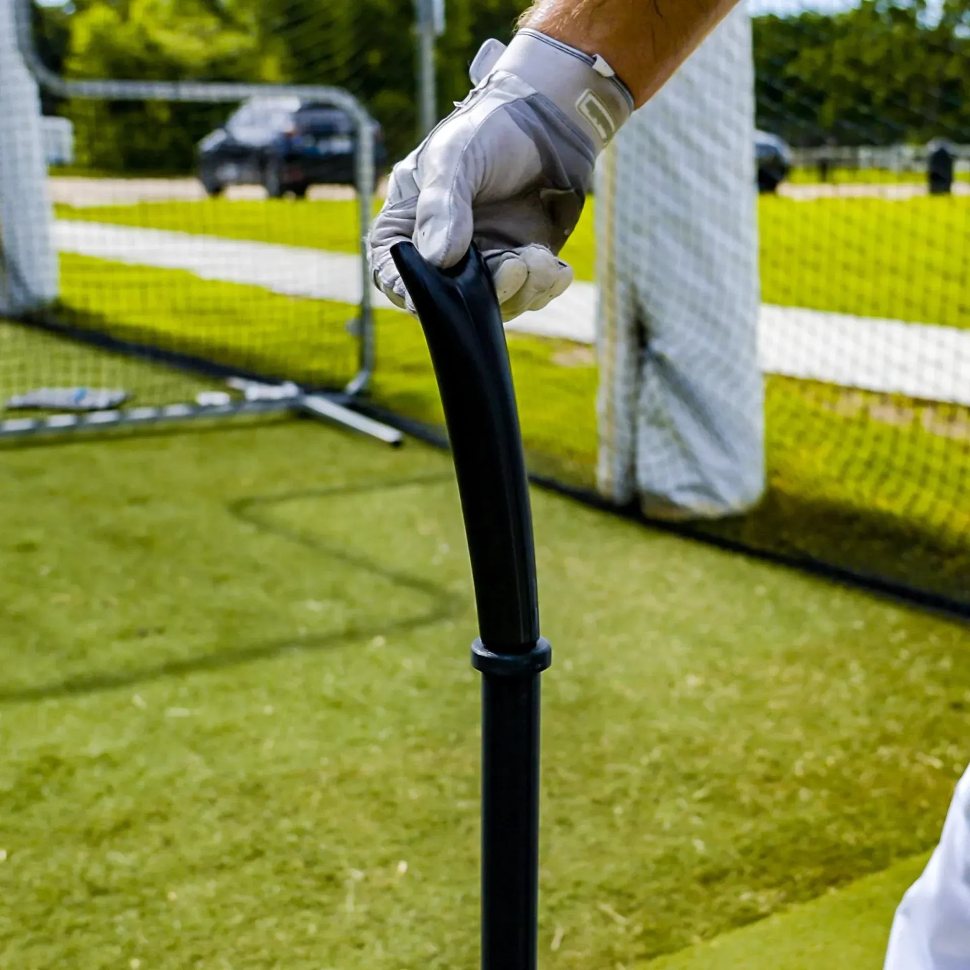 A person wearing gloves is holding a bat on a baseball field