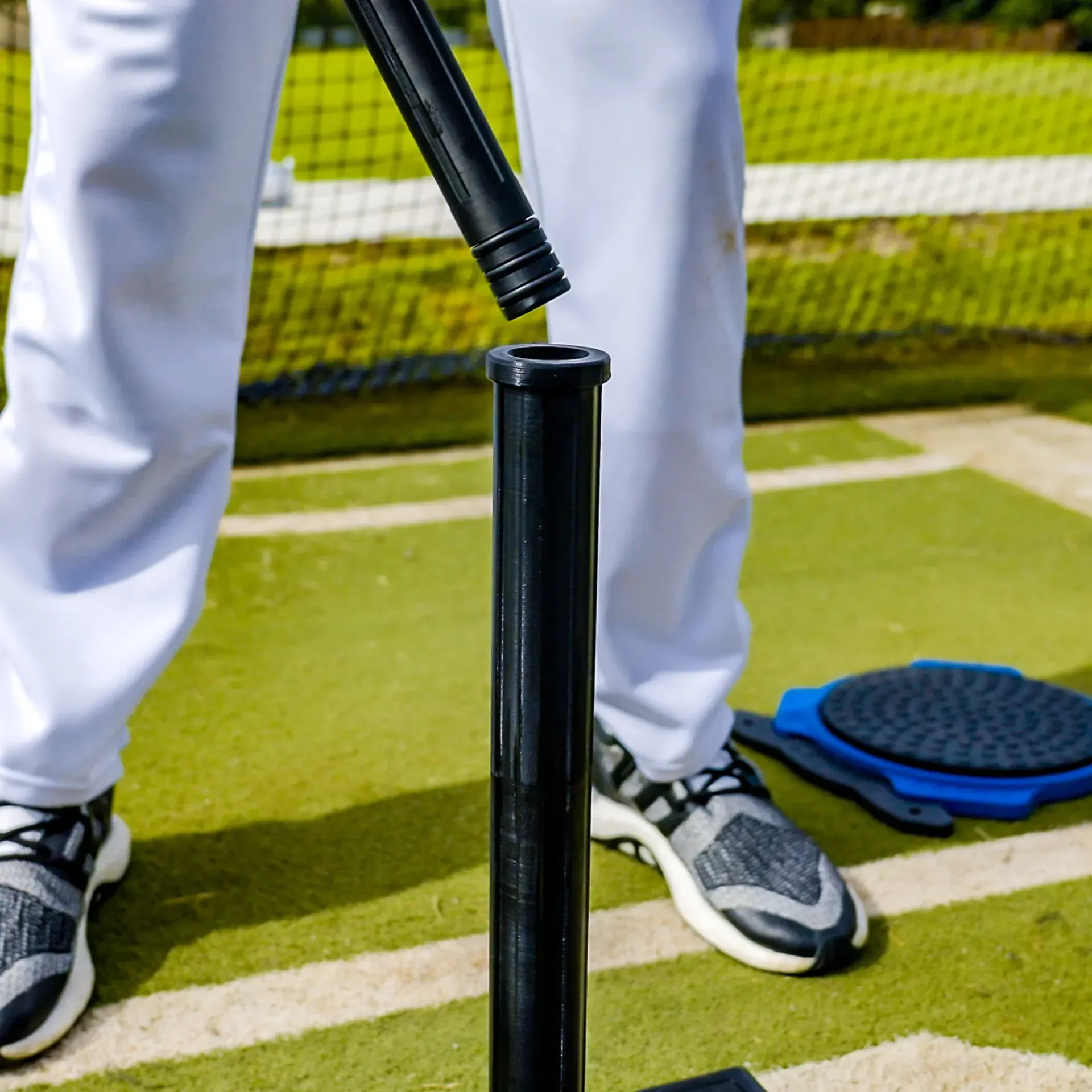 A baseball player is standing next to a batting tee