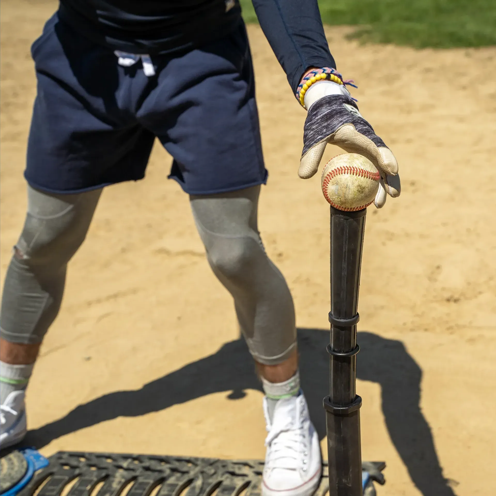 A person holding a baseball on a batting tee