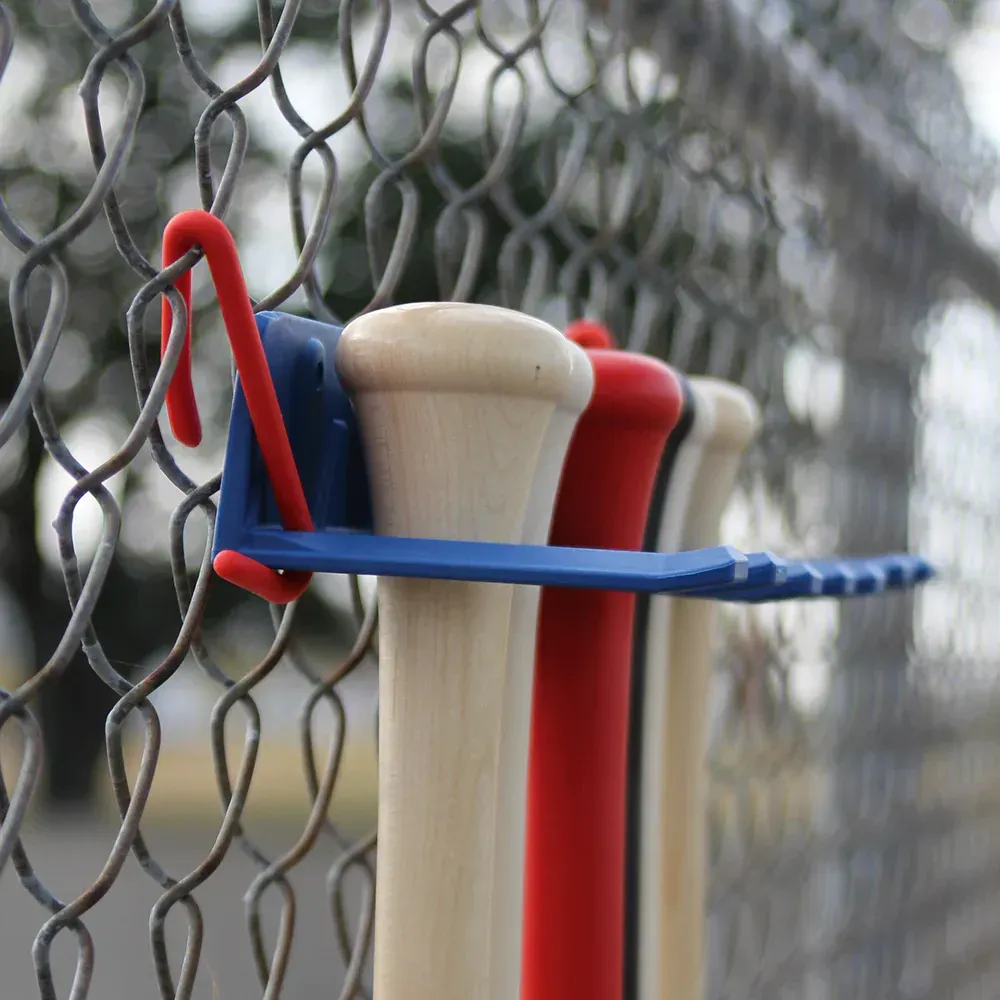 A bunch of baseball bats hanging on a chain link fence