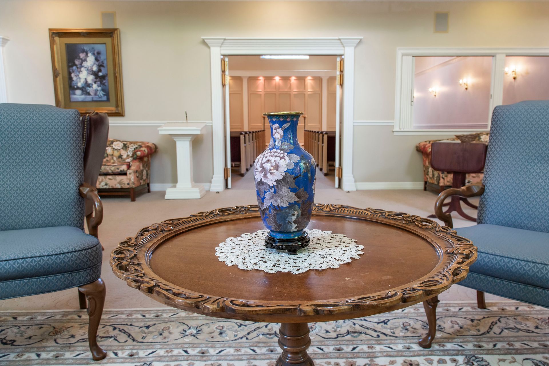 A room with chairs, table, and vase. Doorway leads to another room.