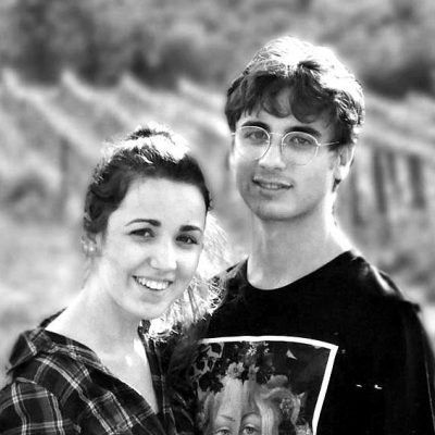 Winemakers of Ejamu posing outdoors, with a vineyard in the blurred background.