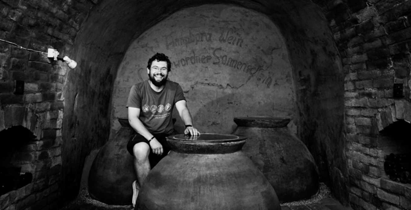 A winemaker sits inside a cellar at Zillinger, surrounded by large clay fermentation vessels.