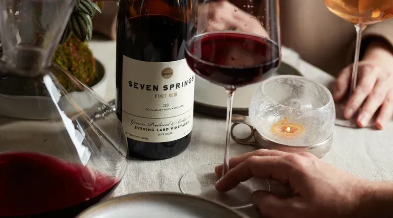 Bottle of Evening Land red wine and glass with wine.