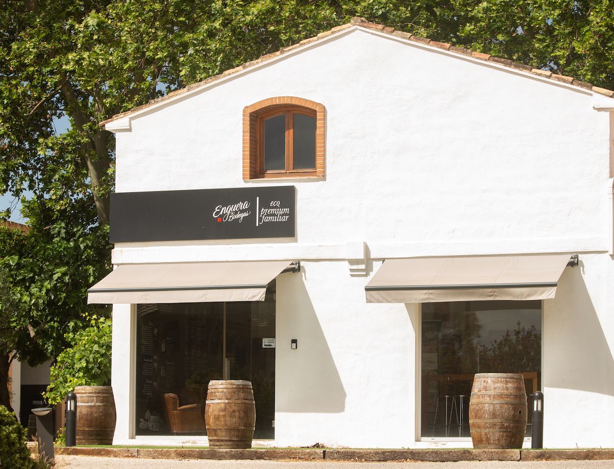 White building with two barrels outside, and a sign that reads
