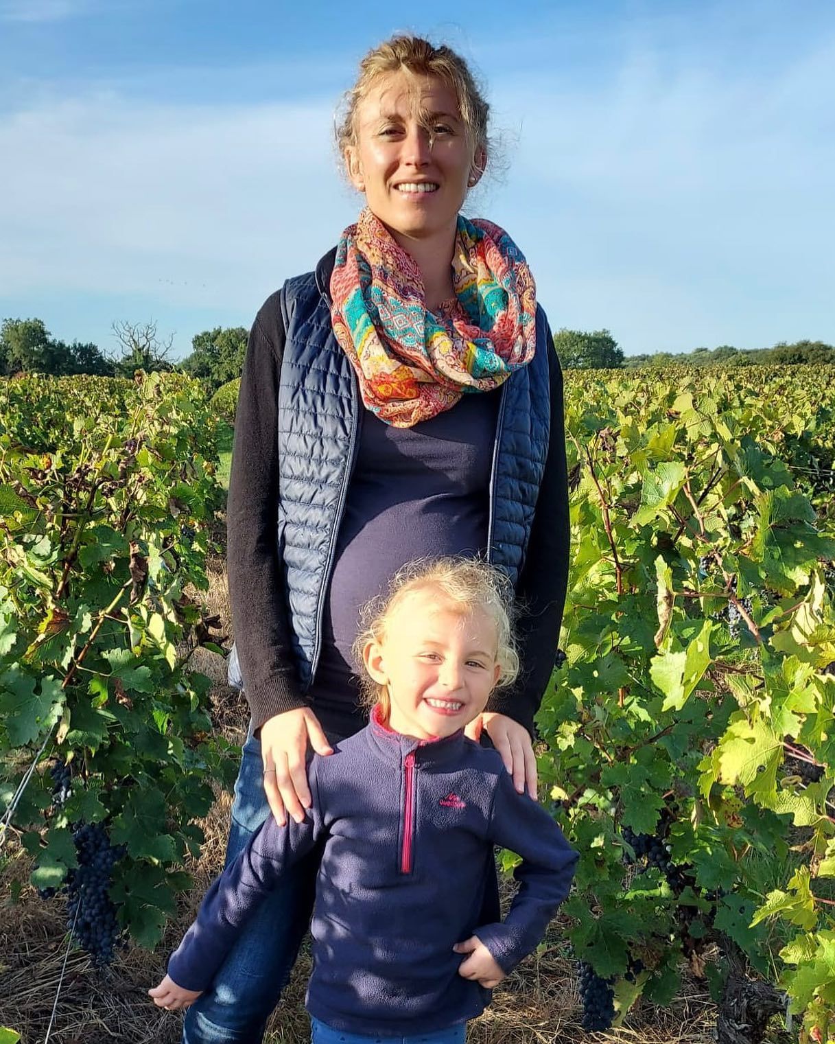 Pregnant woman and young child smiling in Château Saint Hilaire vineyard