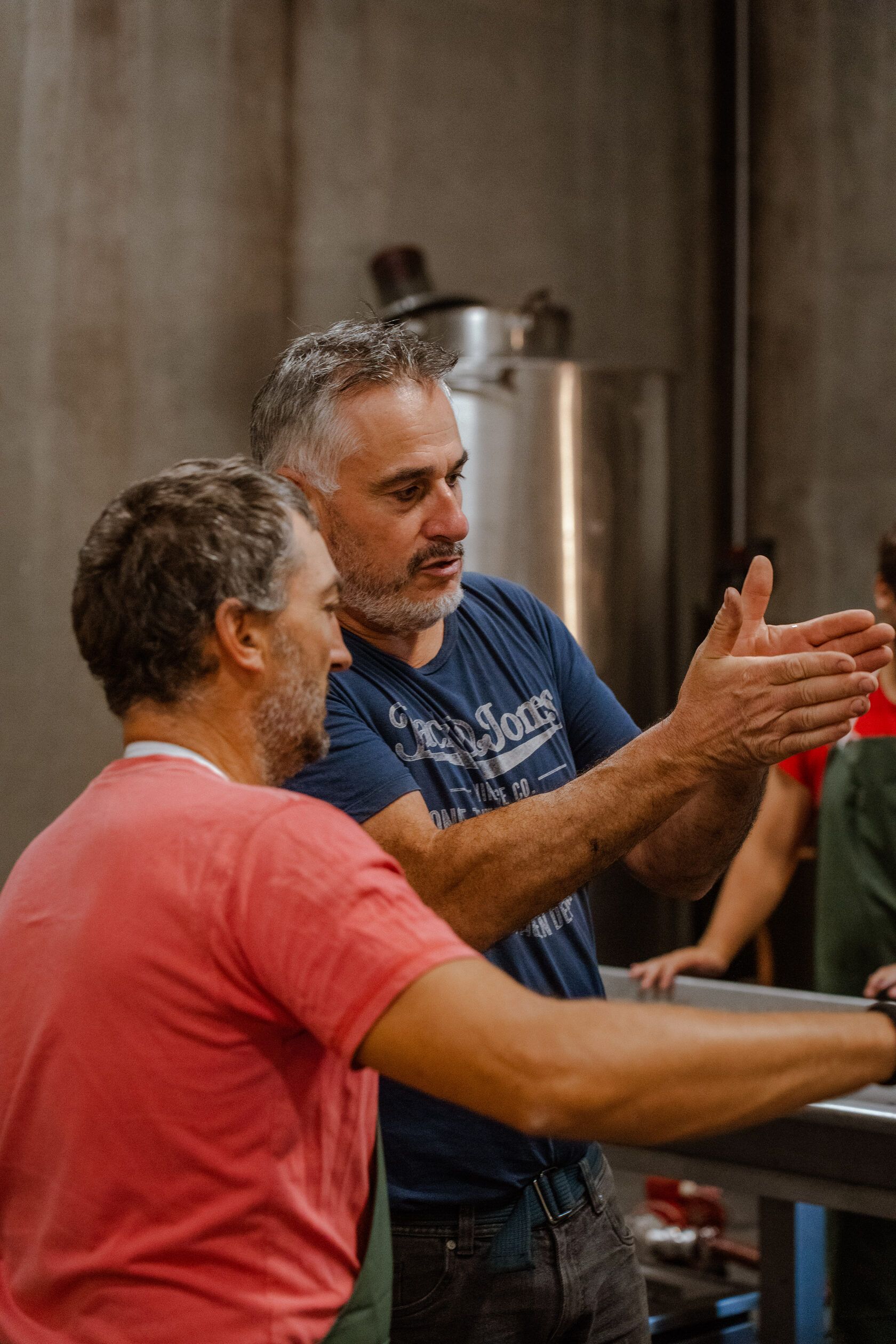 A winemakers and a worker of Château Tour des Termes talking in the winery.