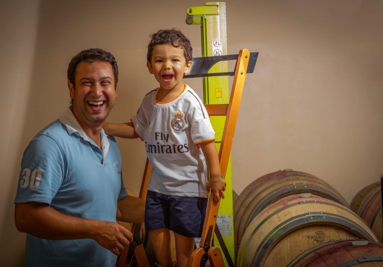 Alberto Voerzio and his son laughing in a cellar.