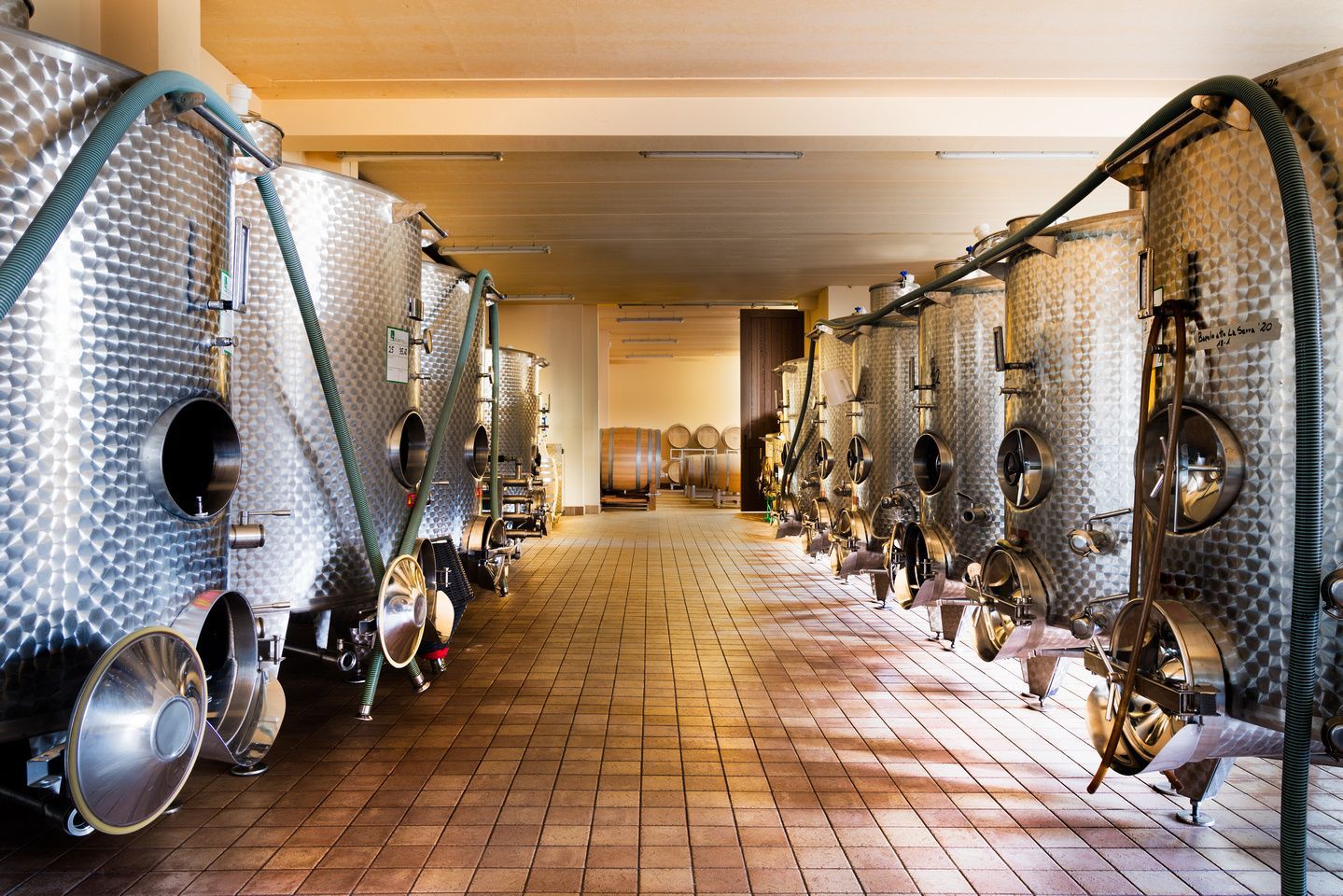 Wine fermentation tanks in a cellar with tiled floors, at Alberto Voerzio winery