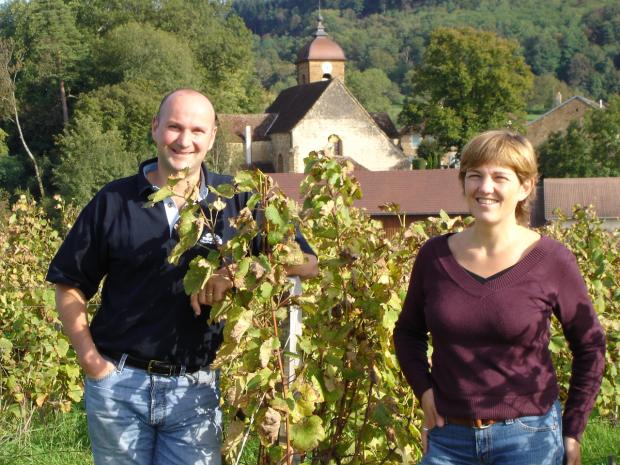 Tissot winemaker in the vineyard, with building in the background.