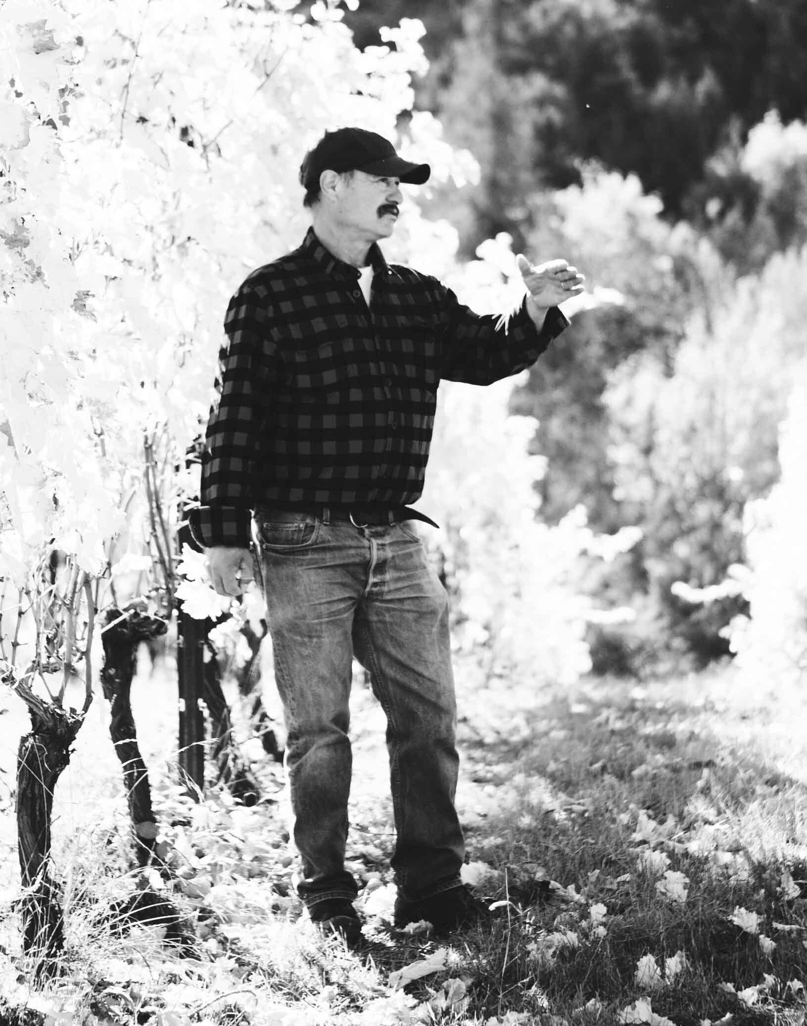 Black and white photo of a man gesturing in Cooper Mountain vineyard