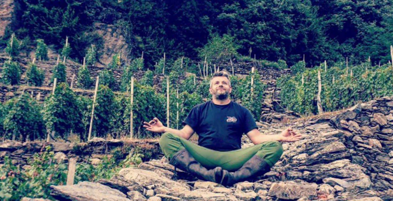 Man meditating in Barbacàn vineyard, wearing boots and green pants.