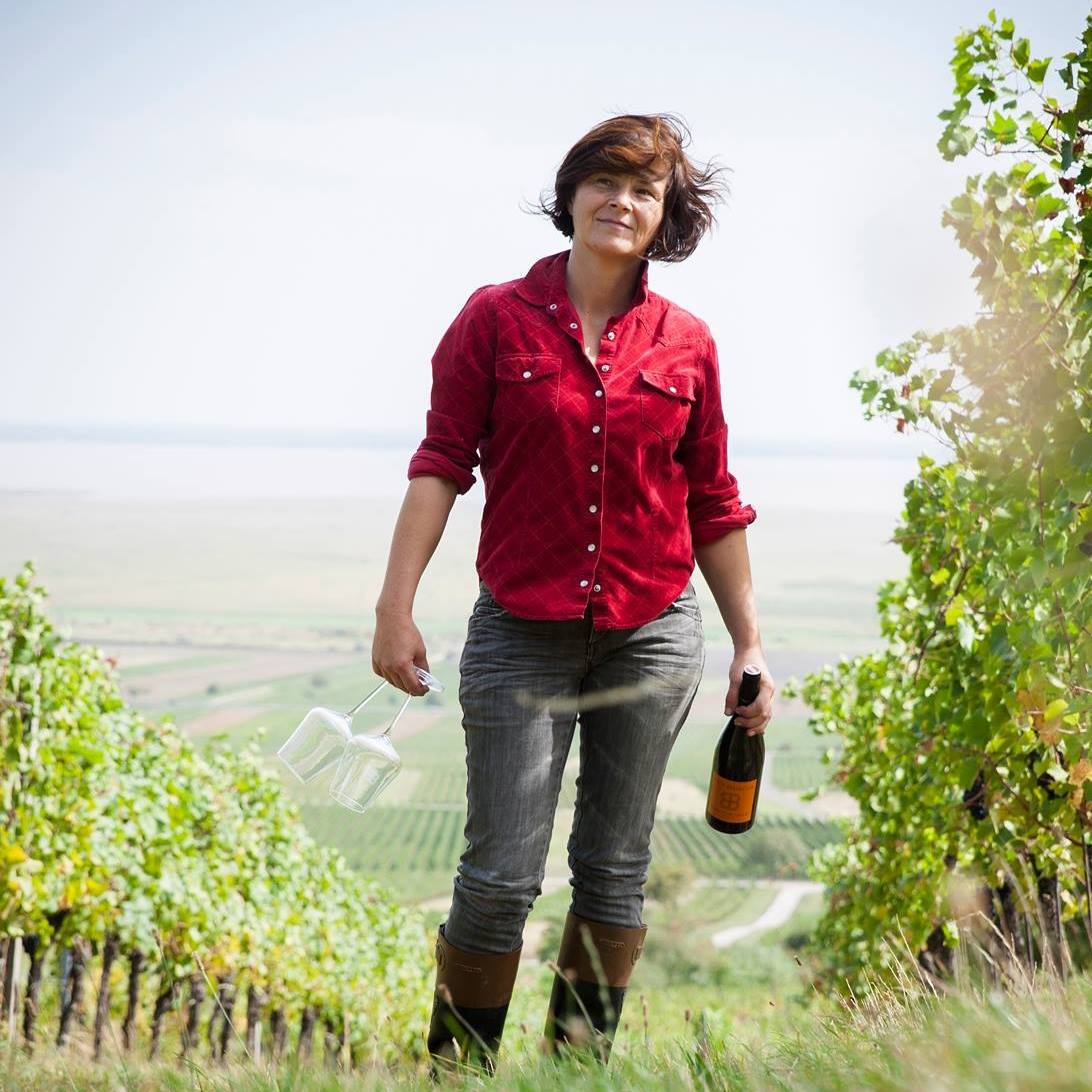 Woman holding a wine bottle and glasses in Birgit Braunstein vineyard.