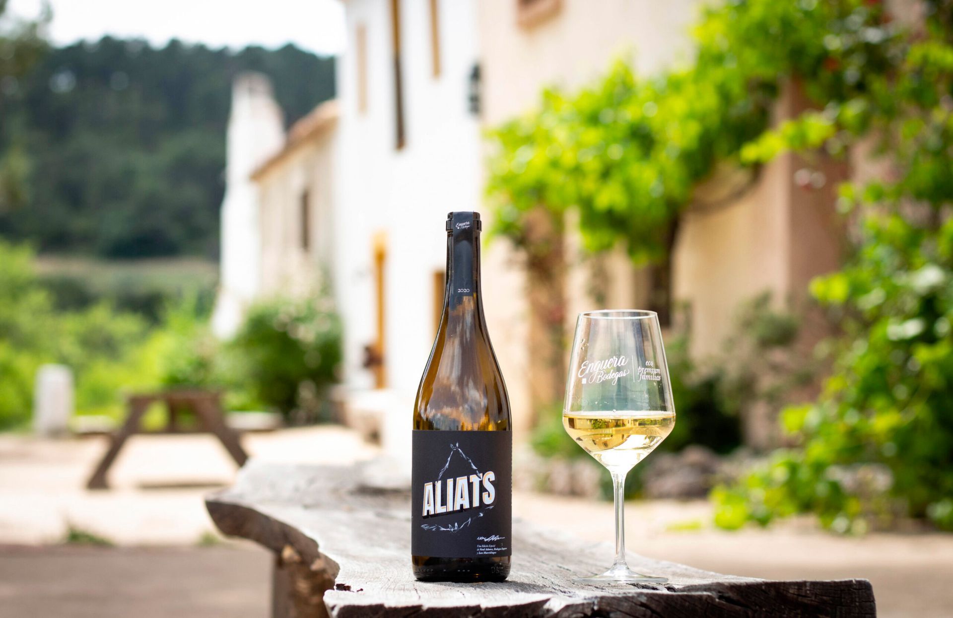 Aliats wine bottle with a glass on wooden surface, at Bodegas Enguera