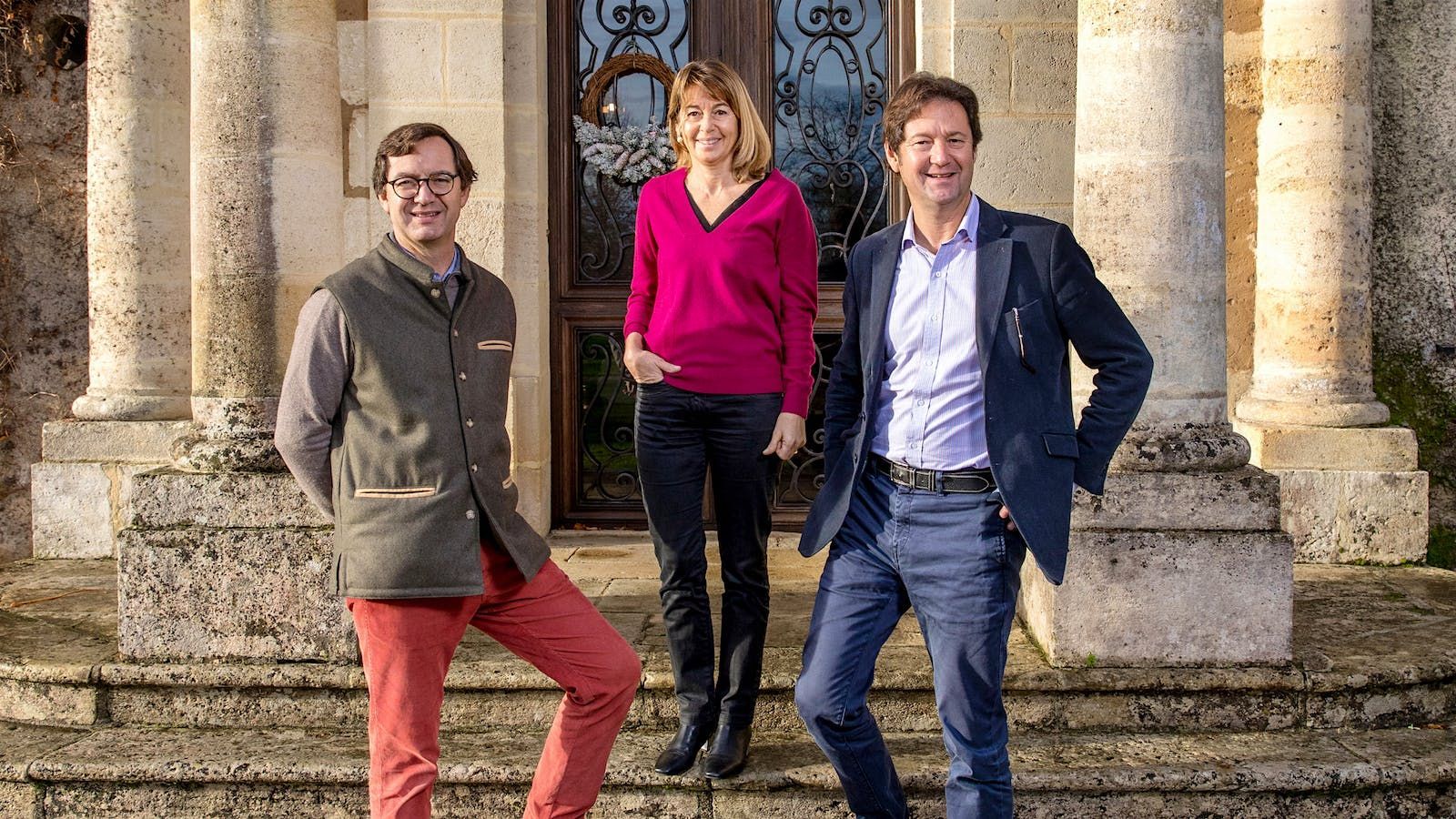 The Carbonieux Family stand on steps in front of a building with columns and a decorative door.