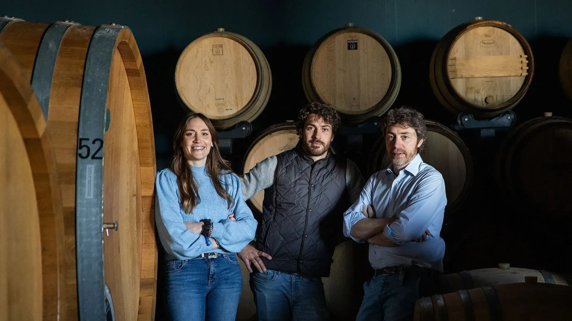 Tean of Cordero San Giorgio posing in a wine cellar with wooden barrels.