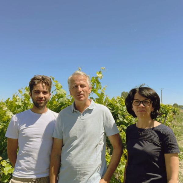 Three people standing in a Olga Raffault vineyard, on a sunny day.