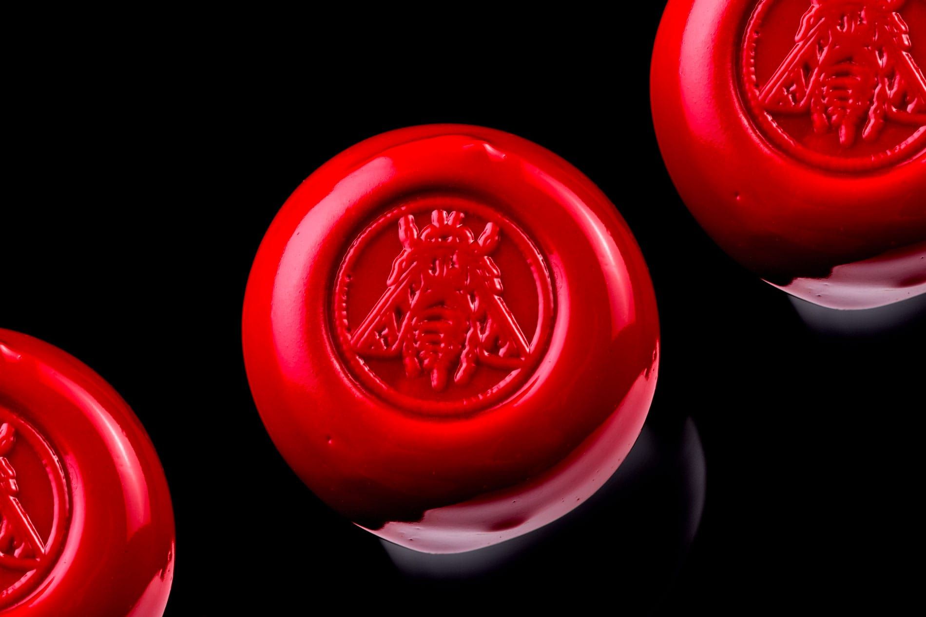 Red wax seals with an embossed insect design on a black background.