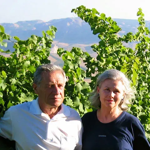 Winemakers of Di Giovanna standing in a vineyard, with rolling hills in the background.