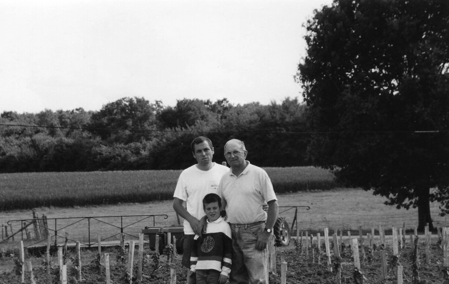 Champ des Treilles family posing for photo in field.  A field and trees in the background.