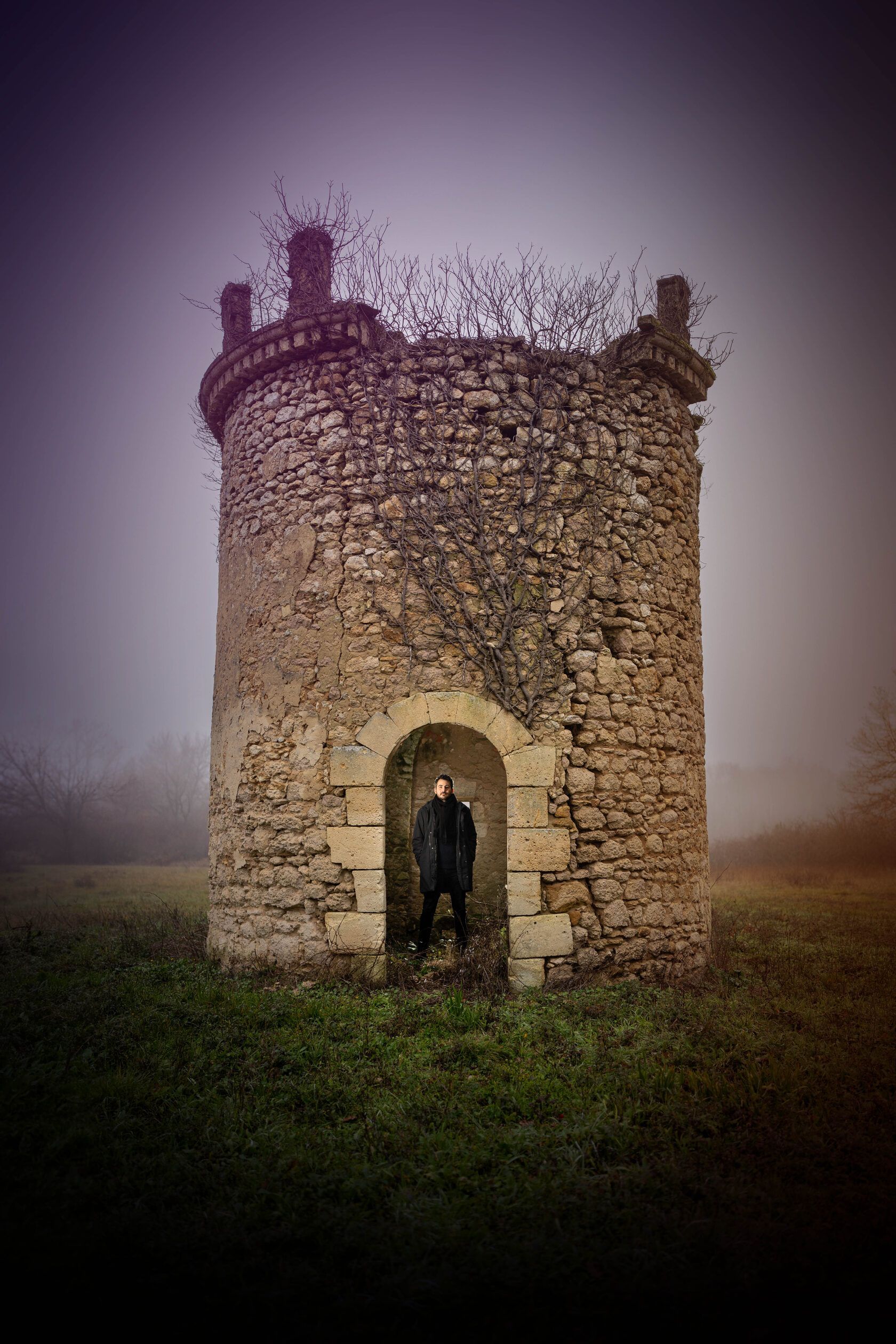 Owner of Château Tour des Termes standing in the doorway of a stone tower ruin.