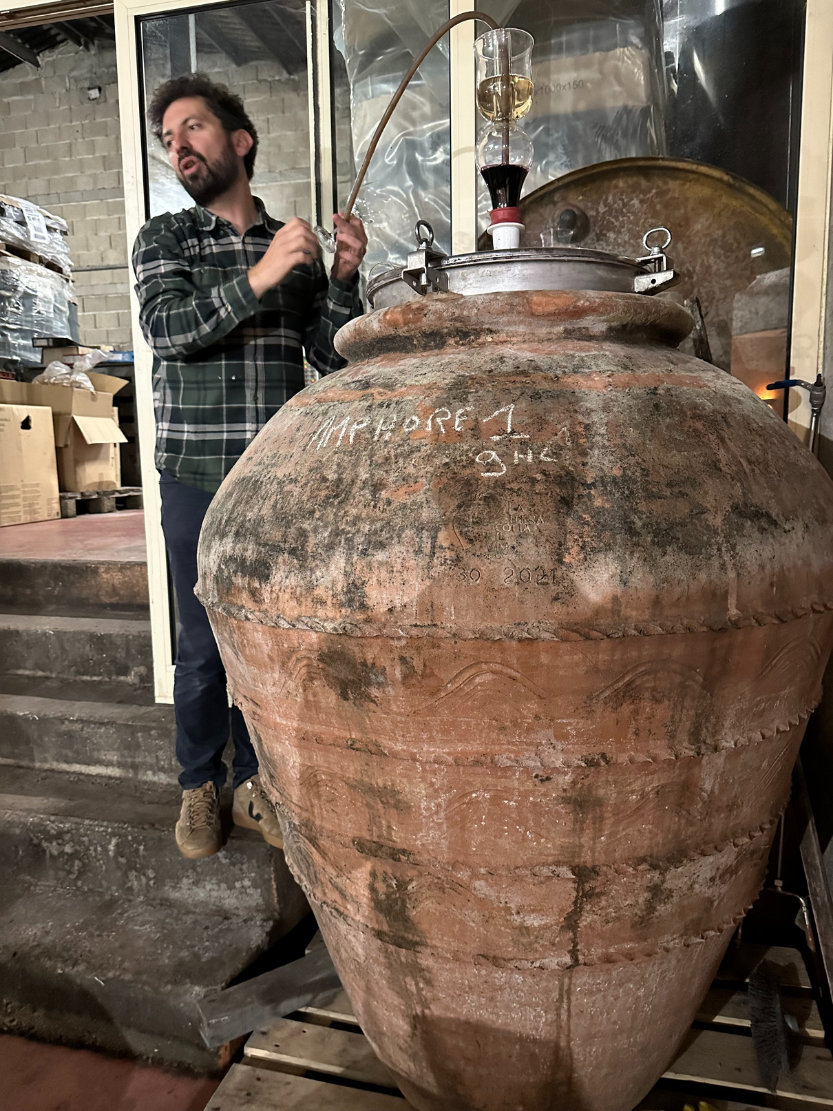 Château Haut Grelot winemaker working with a clay amphora in the winery cellar.