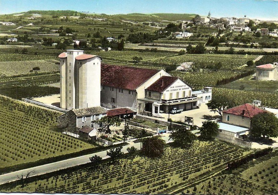 Cave de Cairanne building with a large silo and surrounding vineyards.