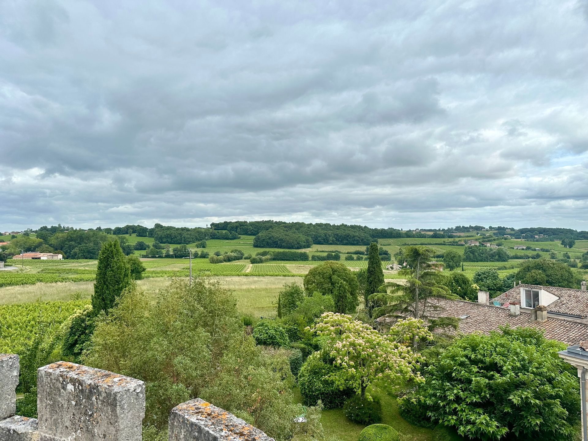 Peybonhomme-les-Tours - Green fields and trees under a cloudy sky, seen from a stone wall.