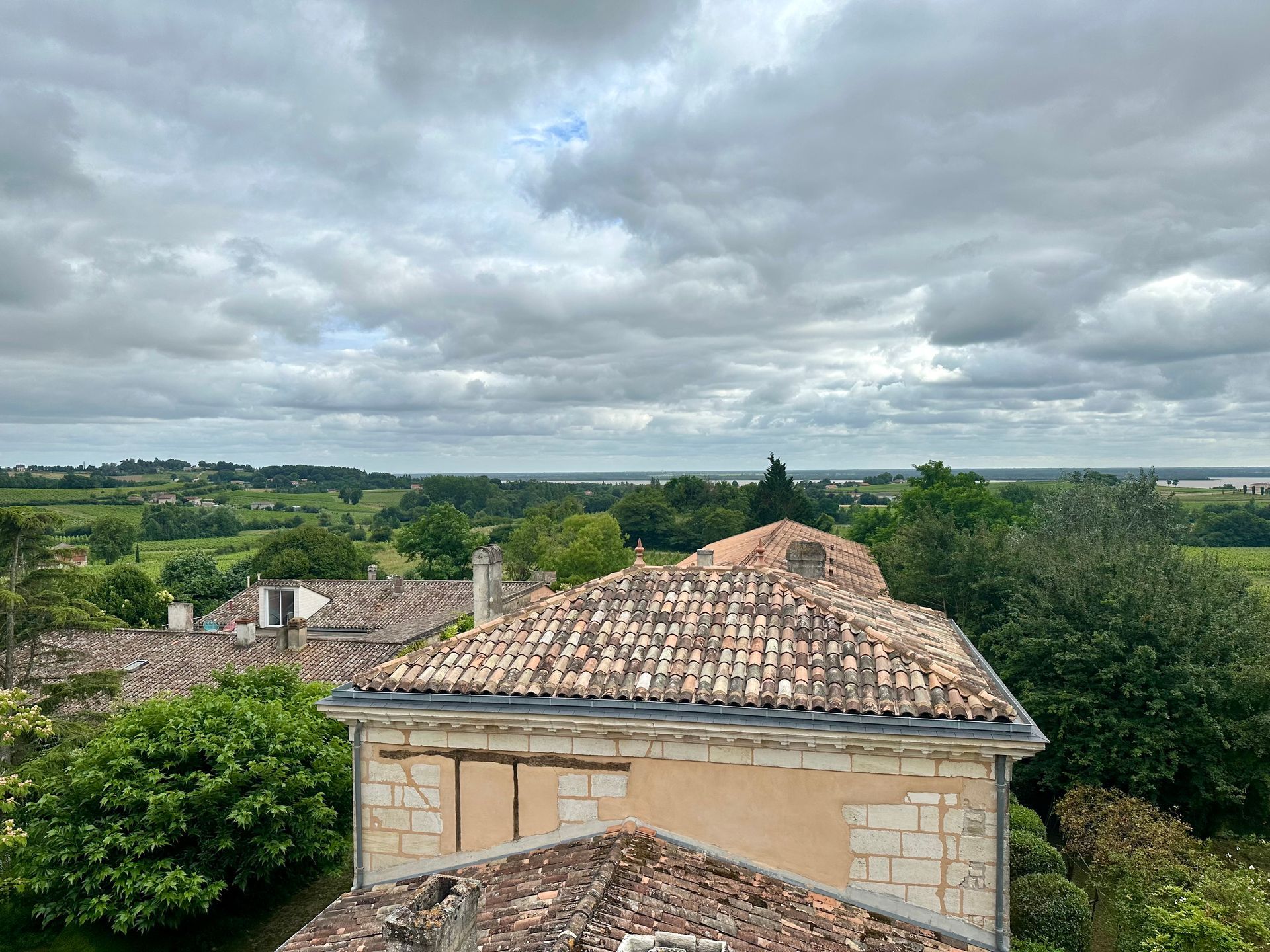 Peybonhomme-les-Tours - Overcast sky over tiled rooftops and green landscape.
