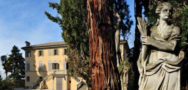 Venturini Baldini historic estate framed by cypress trees and classical sculpture in Emilia-Romagna.