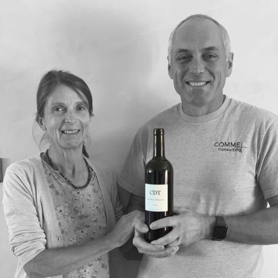 Champ des Treiller winemakers holding a bottle of wine; both smiling at the camera.