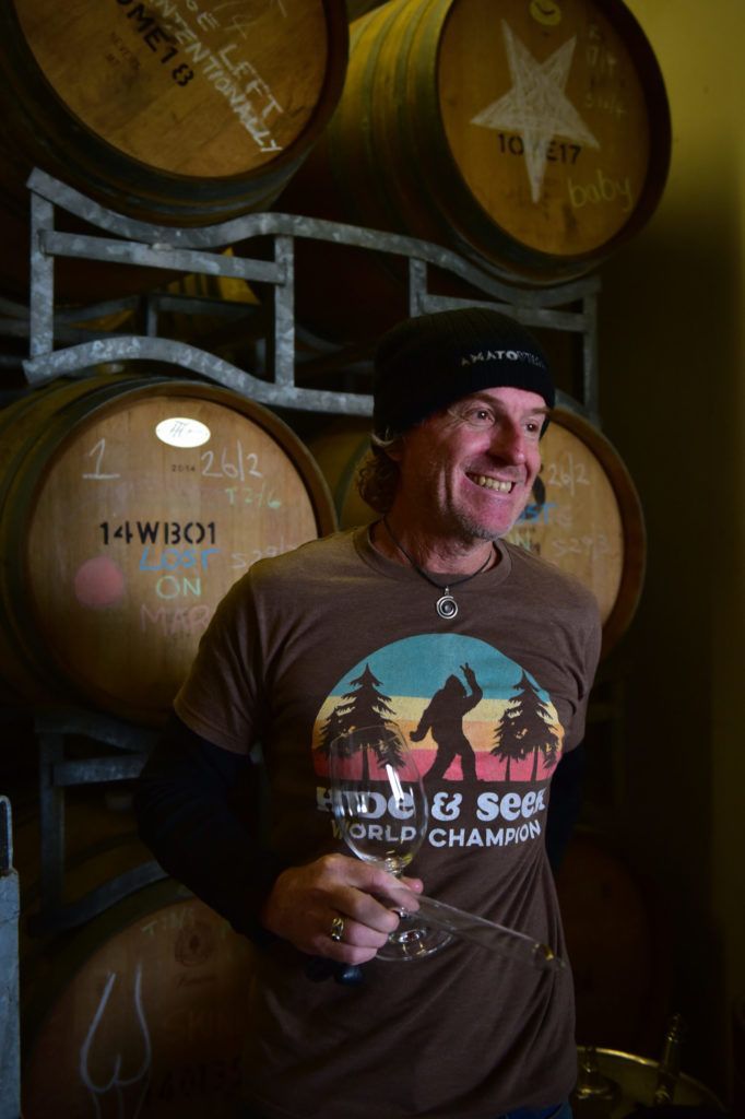 Winemaker of Amato Vino holding a tasting glass in the barrel cellar.