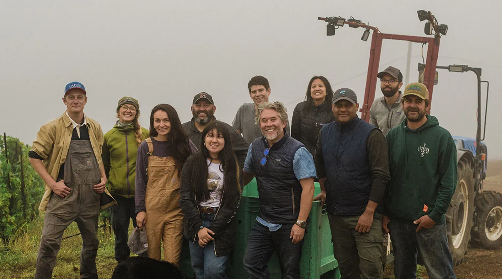 Team of Evening Land posing by a tractor, in the vineyard.