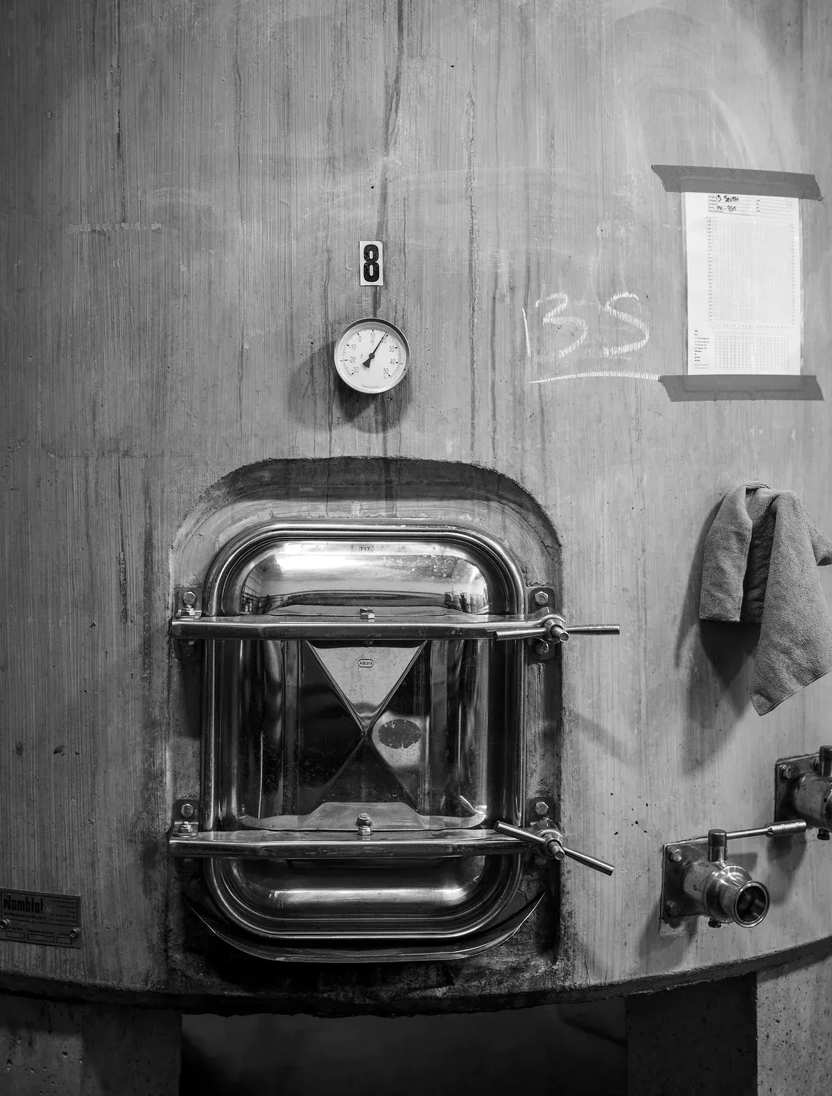 Stainless steel tank door with temperature gauge on a wood-clad tank at Evening Land