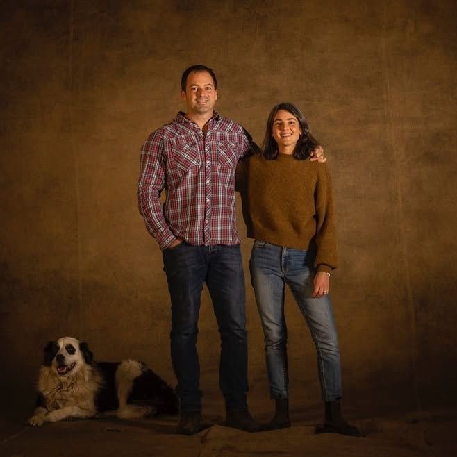 Winemakers of Château la Grolet, with a dogn and a brown backdrop.