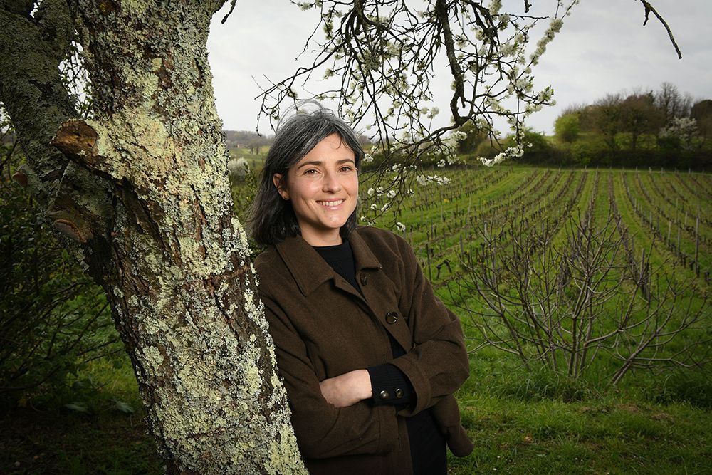 Winemaker of Peybonhomme-les-Tours leaning on a tree, with vineyard in background.