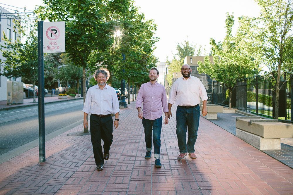 Winemakers of Evening Land walking along a brick sidewalk with trees in the background.