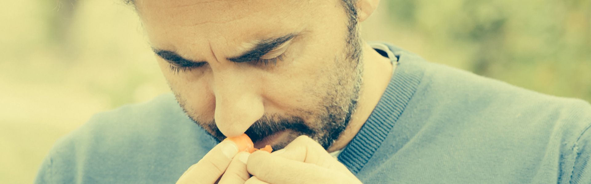 Man holding a grape close to his nose, at Rivetto