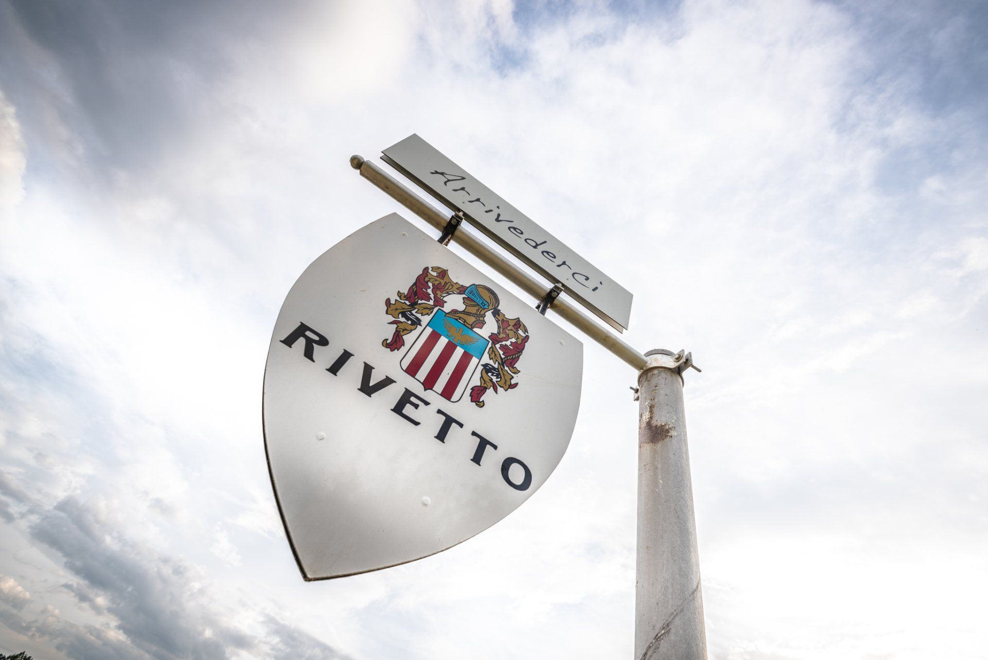 Sign for Rivetto winery, a metal shield shape with the name and emblem.