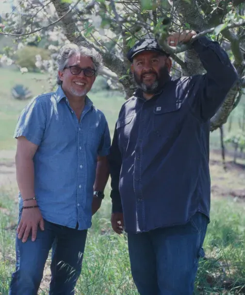 Two Sandhi winemakers standing in the vines, smiling.