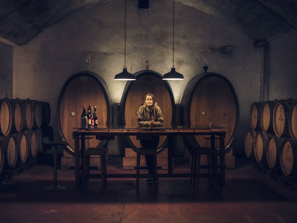 Sandra Bravo of Sierra del Toloño standing in the winery cellar, surrounded by large oak barrels