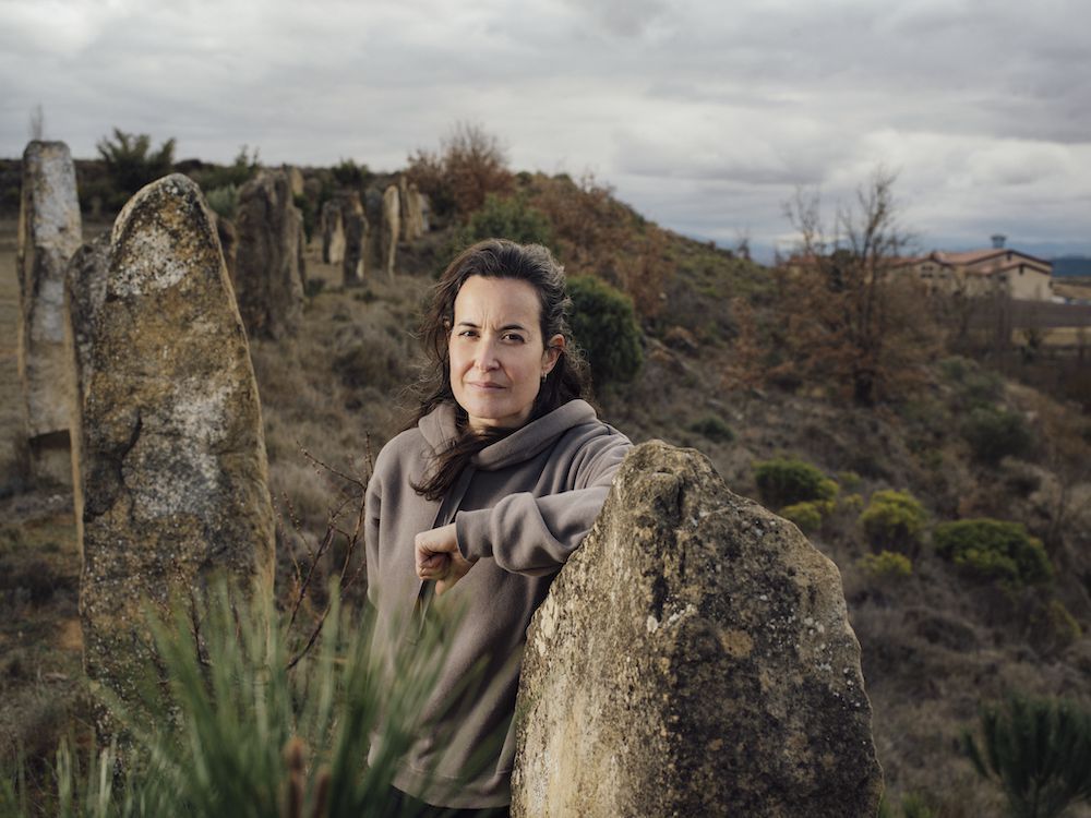 Sandra Bravo standing among stone markers in the vineyard