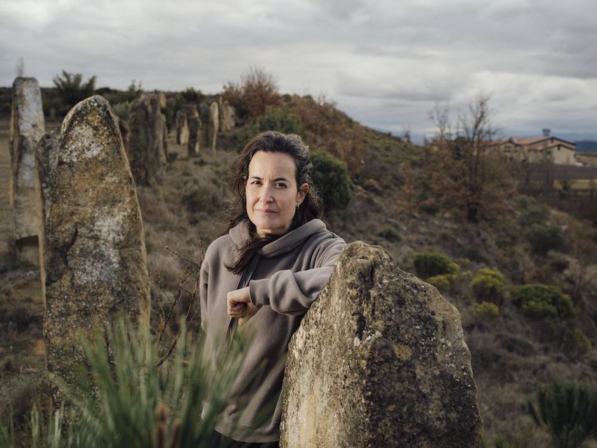 Sierra de Toloño winemaker standing by weathered stone pillars in a field.