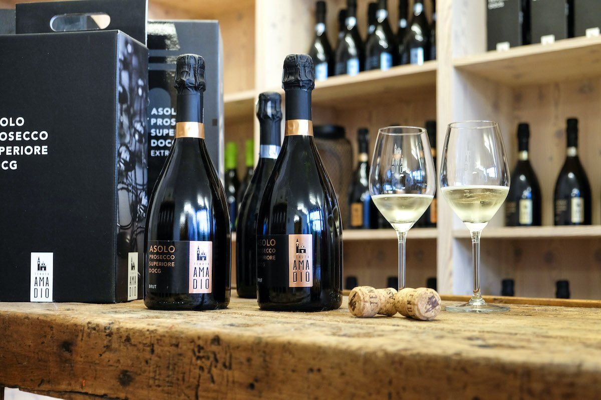 Three bottles of sparkling wine, glasses, and corks on a wooden surface.