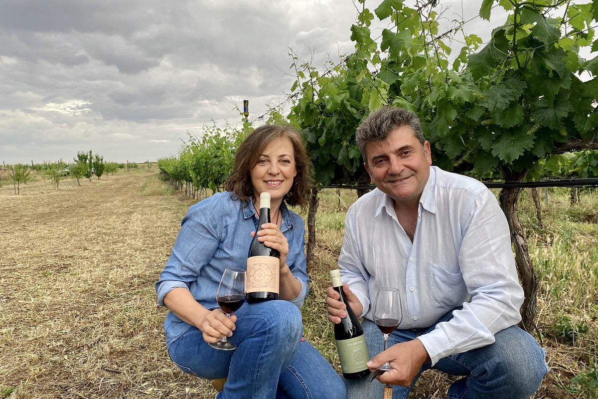 Uva de Vida winemakers sitting in the vineyard, holding wine bottles and glasses among the vines