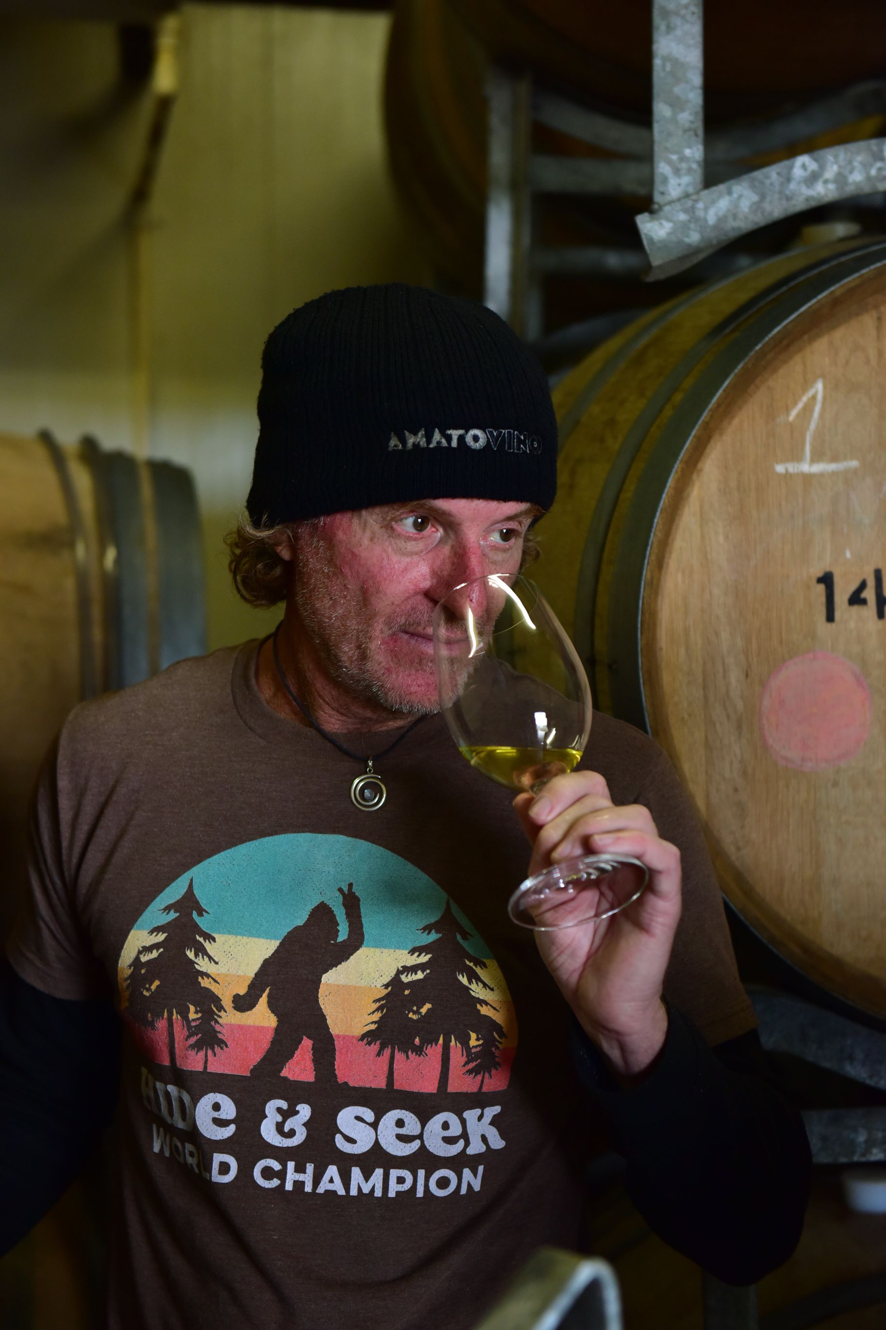 Brad, winemaker at Amato Vino, smelling a glass of white wine in the barrel cellar.