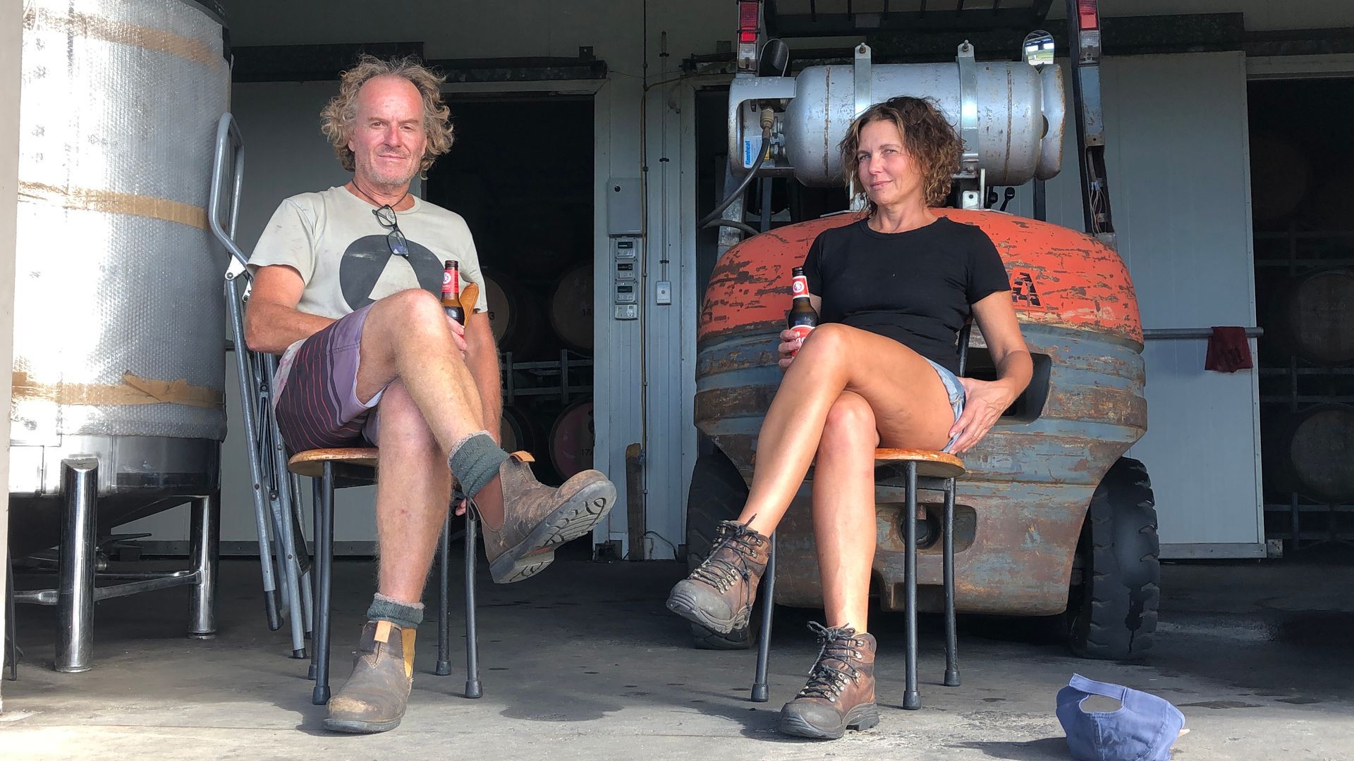Brad and Sharon, winemakers of Amato Vino, seated at the winery holding bottles.
