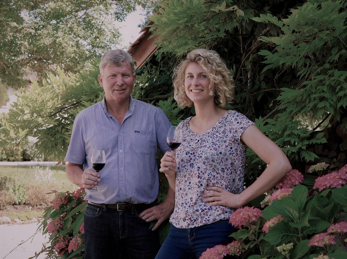 Man and woman holding wine glasses, smiling outdoors, at Château Saint Hilaire