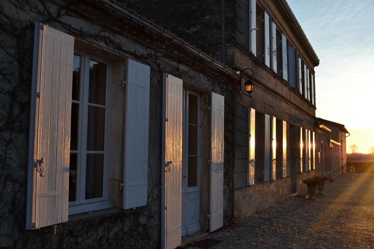 Stone building with white shutters, reflecting the golden light of the setting sun at Château Saint Hilaire