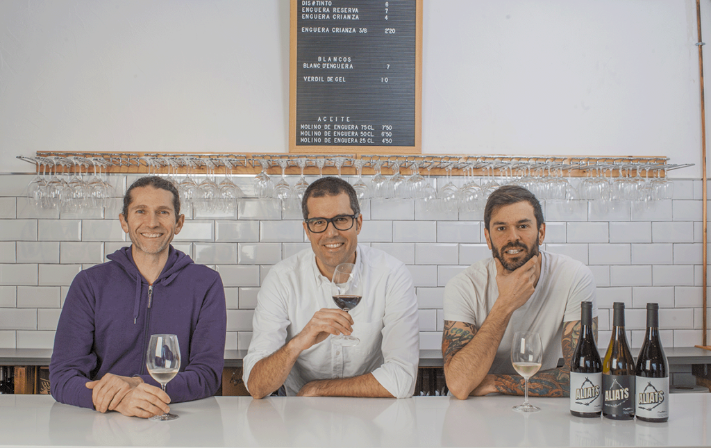 Three men at Bodegas Enguera tasting room, holding wine glasses.